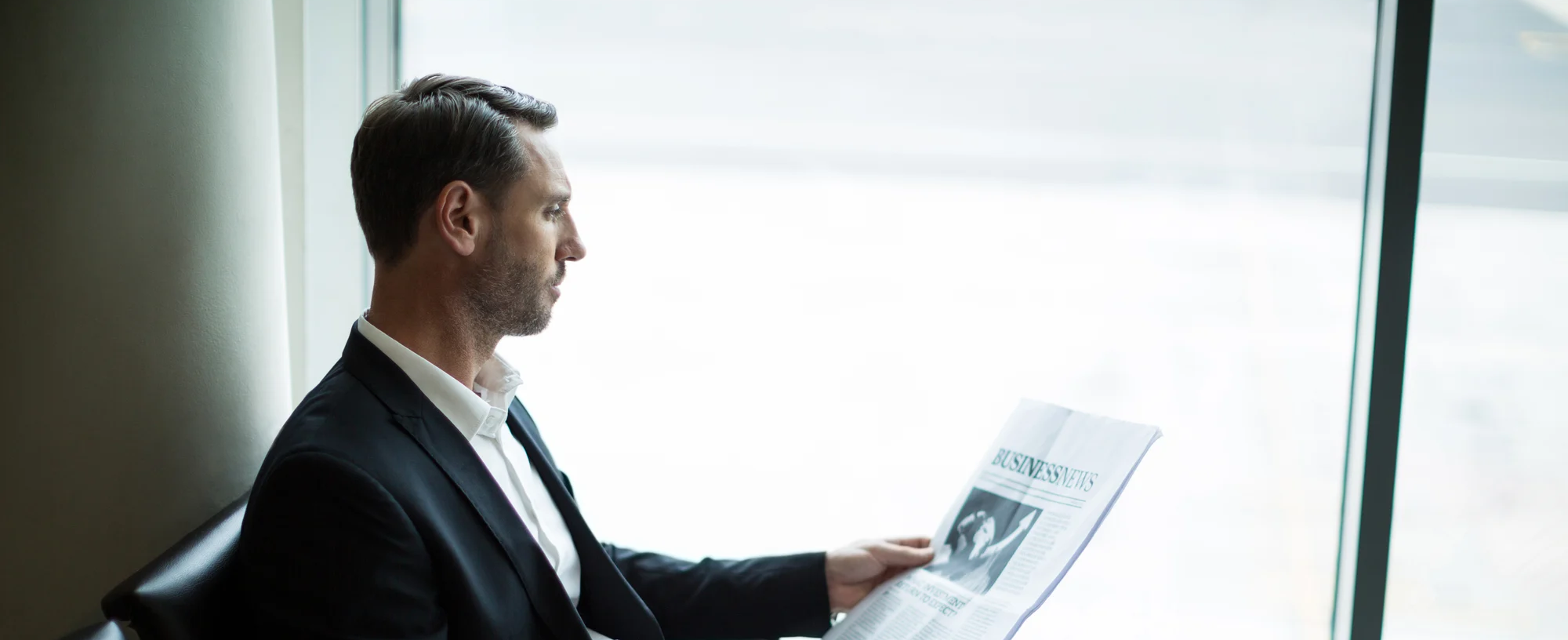 businessman-having-coffee-while-reading-newspaper-waiting-area-wide-1
