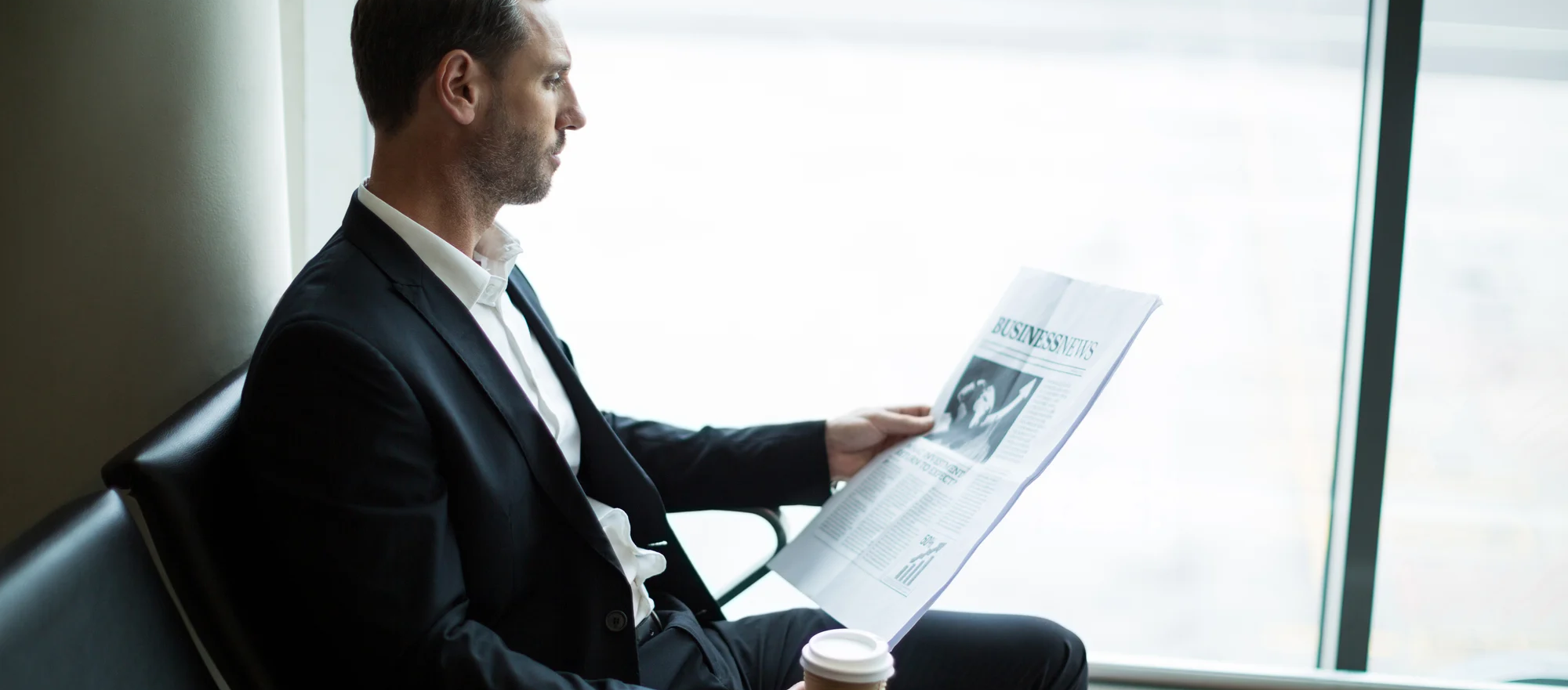 businessman-having-coffee-while-reading-newspaper-waiting-area-wide